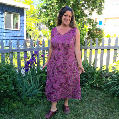 A woman in purple dress standing next to flowers.