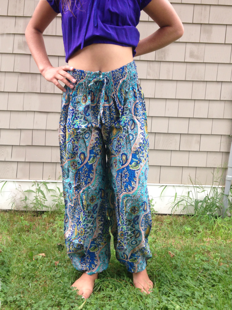 A woman standing in the grass wearing blue pants.