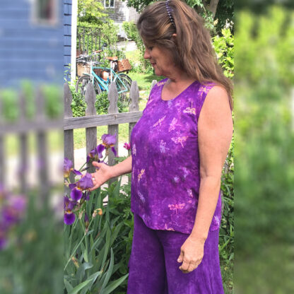 A woman in purple outfit standing next to flowers.