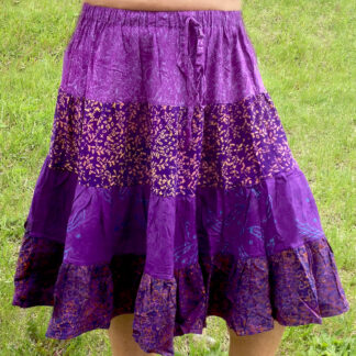 A person wearing purple skirt standing in grass.