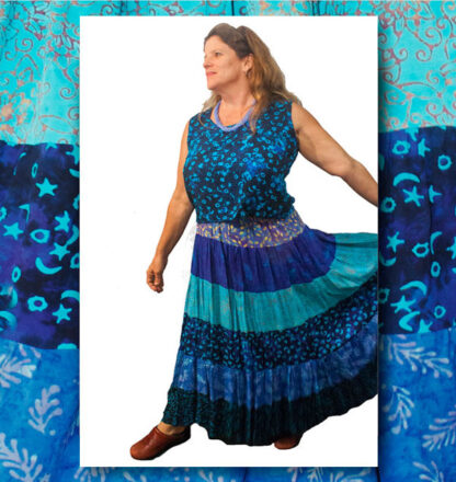 A woman in blue and black dress standing next to a wall.