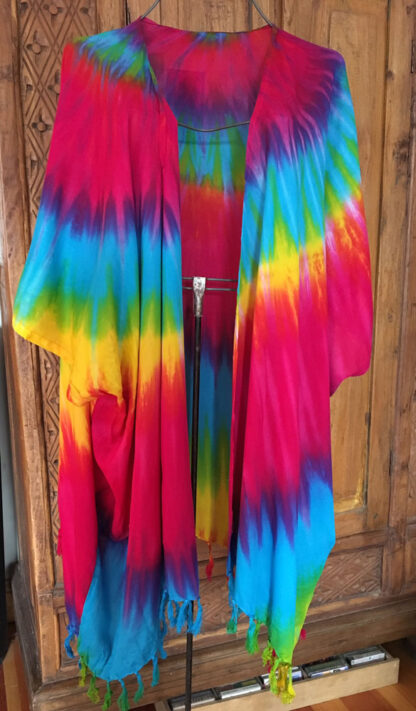 A colorful tie dye jacket hanging on the wall.