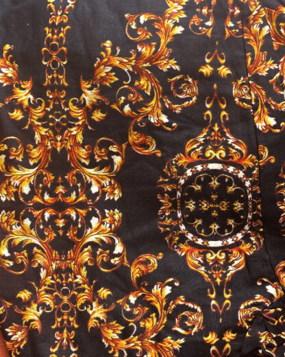 A close up of the fabric with gold and black designs