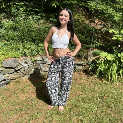 A woman standing in the grass wearing black and white pants.