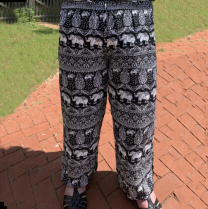 A person standing on brick path wearing black and white elephant print pants.