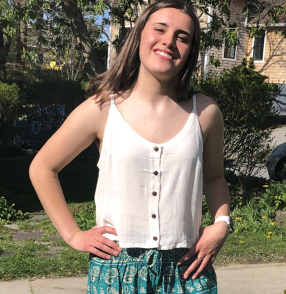 A girl standing outside wearing a white top.