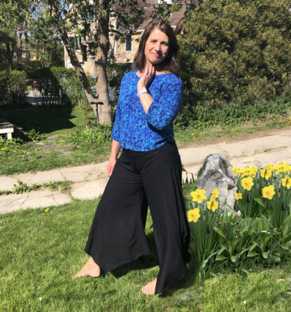 A woman standing in the grass near some yellow flowers.
