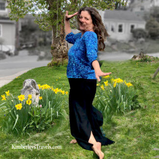 A woman in blue shirt and black skirt standing on grass.