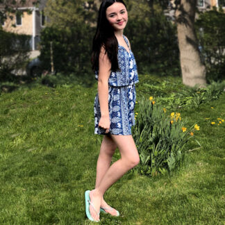 A girl in blue dress walking on grass.