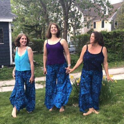 Three women standing in a yard holding hands.