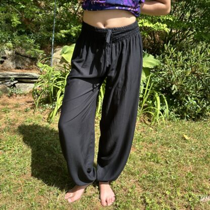 A woman standing in the grass wearing black pants.