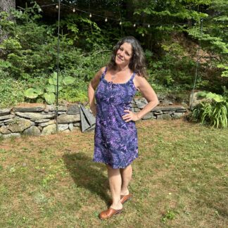 A woman standing in the grass wearing a purple dress.